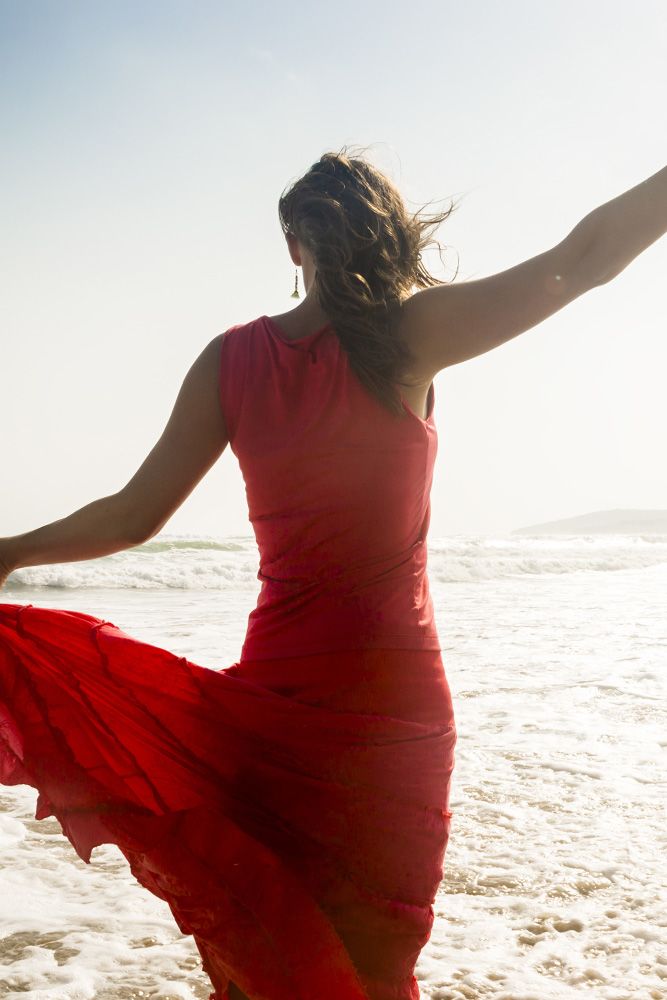 Woman in a red dress holding her hands in the air.
